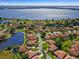 Expansive aerial view of a community boasting stunning water views, lush landscaping, and charming red-tiled roofs at 802 Magnolia Pl, Winter Haven, FL 33884