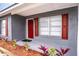 Front entrance with red door, gray brick, and red shutters at 115 7Th Jpv St, Winter Haven, FL 33880