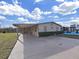 Tan mobile home with carport, landscaping, and paved driveway at 1750 Fox Hill Dr, Lakeland, FL 33810