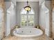 Luxurious soaking tub under arched window with elegant chandelier and tiled surround at 221 Mclean Pt, Winter Haven, FL 33884