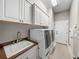 Clean laundry room with cabinets, countertop, sink, washer, dryer, and exterior door at 221 Mclean Pt, Winter Haven, FL 33884