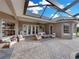 A covered outdoor living space features a stone patio, seating, and views of the yard and neighborhood at 221 Mclean Pt, Winter Haven, FL 33884