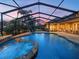 An evening shot of the pool with the hot tub shows the patio and outdoor living area under the screened enclosure at 221 Mclean Pt, Winter Haven, FL 33884