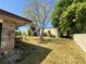 Manicured backyard with lush lawn, mature trees, and a glimpse of the hangar at 25 Aviation Dr, Winter Haven, FL 33881