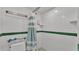 White tiled shower with green accents and a striped curtain at 48 Nottingham Way, Haines City, FL 33844