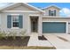Two-story house with gray siding, teal garage door, and landscaping at 245 Hillcrest Dr, Dundee, FL 33838