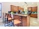Kitchen island with seating, granite counters & wood cabinetry at 2683 Wyndsor Oaks Way, Winter Haven, FL 33884