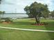 Scenic waterfront view with a large tree, manicured lawns, and a glimpse of the lake in the distance at 333 Lake Howard Nw Dr # 202-A, Winter Haven, FL 33880