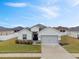 Single-story home with gray garage door and landscaping at 425 Riders Loop, Auburndale, FL 33823