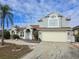 Two-story house with a beige exterior, landscaping, and a two-car garage at 437 Grand Reserve Dr, Davenport, FL 33837