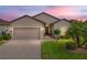 Tan one-story house with two-car garage, landscaping, and paved driveway at sunset at 4505 Back Nine Dr, Winter Haven, FL 33884