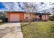 Orange house with fire damage, boarded windows, and a pink garage door at 517 Cipres Cir, Winter Haven, FL 33880