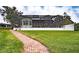 Brick path leads to a spacious backyard with screened pool at 524 Arneson Ave, Auburndale, FL 33823