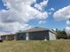 Grey home with back door access and small yard, under cloudy blue skies at 809 Lincoln St, Babson Park, FL 33827