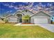 Gray house with two-car garage, palm trees, and well-maintained lawn at 1932 Southern Dunes Blvd, Haines City, FL 33844