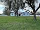 Ranch-style home featuring a light-blue exterior, metal roof and situated on a spacious grassy lot with mature shade trees at 2510 Lakefront Dr, Lake Wales, FL 33898