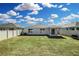 Spacious backyard with green grass, enclosed by a white vinyl fence, and featuring a covered patio at 264 Spirit Landings Cir, Winter Haven, FL 33880