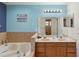 A well-lit bathroom boasting double sinks, a sizable mirror, and an adjacent soaking tub at 2772 Indian Pipes Trl, Frostproof, FL 33843