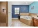 Serene primary bathroom with a soaking tub, blue accent wall, and separate shower with beige tiling at 2772 Indian Pipes Trl, Frostproof, FL 33843