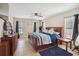 Comfortable main bedroom with wood furniture, ceiling fan, and natural light from two windows with blue curtains at 2772 Indian Pipes Trl, Frostproof, FL 33843