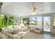 Bright sunroom with tile flooring, ceiling fan and view of dock and lake beyond the windows at 462 Sweetwater Way, Haines City, FL 33844