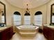 Bright bathroom featuring a large soaking tub, chandelier, and abundant natural light at 1006 W Lake Hamilton Dr, Winter Haven, FL 33881
