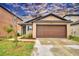 Tan house with brown garage door and landscaping at 1713 Yellow Trl, Lakeland, FL 33801
