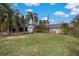 Single-story home with a large yard, palm trees, and a spacious driveway at 208 Limpkin Ln, Frostproof, FL 33843