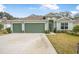 Two-story house with a green exterior, three-car garage, and landscaped lawn at 3033 Adrian Dr, Ormond Beach, FL 32174