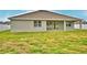 The back exterior of the house showing the covered patio and green yard at 304 Denna Ln, Auburndale, FL 33823