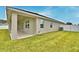 A side exterior view of the home showcasing the covered patio and lush green lawn at 304 Denna Ln, Auburndale, FL 33823