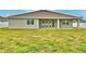 The back exterior of the house showing the covered patio and lush green yard at 304 Denna Ln, Auburndale, FL 33823