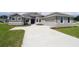 Charming single-Gathering home with stone accents, light gray paint, attached garage, and a large front yard at 304 Denna Ln, Auburndale, FL 33823