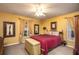 Comfortable bedroom with a cozy red bed, plush carpeting, and warm, inviting lighting at 3746 Red Oak Ct, Lake Wales, FL 33898