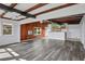 Living room with exposed wood beams, wood-paneled wall, and kitchen access at 557 Thornburg Rd, Babson Park, FL 33827