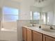 Bathroom featuring a double sink vanity, soaking tub, and frosted windows for privacy at 746 Platypus Ct, Kissimmee, FL 34759