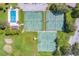 Aerial view of tennis courts and community pool with lush, mature landscaping at 768 Canberra Rd, Winter Haven, FL 33884