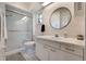 Cozy bathroom with a walk-in shower, featuring a tiled floor, white vanity with sink, and round mirror at 768 Canberra Rd, Winter Haven, FL 33884