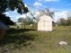 A light-pink shed in a grassy yard with trees at 8150 State Road 60 E, Bartow, FL 33830