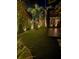 Lush backyard with ambient lighting and a covered patio perfect for outdoor entertaining and serene relaxation at 1 Casarena Ct, Winter Haven, FL 33881