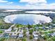 Expansive aerial view of waterfront homes surrounding a picturesque lake under a partly cloudy sky at 106 Lake Sears Dr, Winter Haven, FL 33880