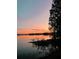 Stunning sunset reflecting on the tranquil lake with lush vegetation and silhouetted trees at 106 Lake Sears Dr, Winter Haven, FL 33880