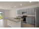 Spacious kitchen features an island, stainless steel appliances, and gray cabinets at 1157 Blue Jay Dr, Davenport, FL 33837