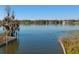 Scenic waterfront view featuring calm water, lilly pads and homes in the distance under a blue sky at 148 Lake Otis Rd, Winter Haven, FL 33884