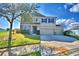 Two-story tan home with blue shutters, stone accents, a well-manicured lawn, and an attached two-car garage at 1510 Shorewood Dr, Auburndale, FL 33823