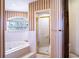 Bathroom showing the bathtub area with a window view and glass-door shower in an alcove at 1815 Adams Barn Rd, Lake Alfred, FL 33850