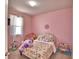 Cozy bedroom with pink walls, patterned bedding, and natural light from the window at 200 Summershore Dr, Auburndale, FL 33823