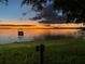 Beautiful waterfront sunset view overlooking the water, dock, and grassy lawn at 253 Blackwell Villa Cv, Babson Park, FL 33827