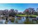Tranquil lakefront setting with a dock, lush greenery, and a beautiful home in the background at 3312 Eagles Trce, Winter Haven, FL 33884