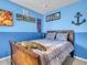 A cozy bedroom featuring blue walls, light-colored carpet, and a wooden bed frame with striped bedding at 3526 Warbler Way, Kissimmee, FL 34746